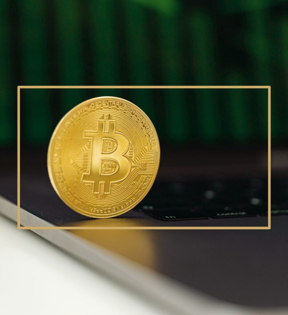 Goldene Bitcoin-Münze steht aufrecht auf einer Laptop-Tastatur vor grünem Hintergrund